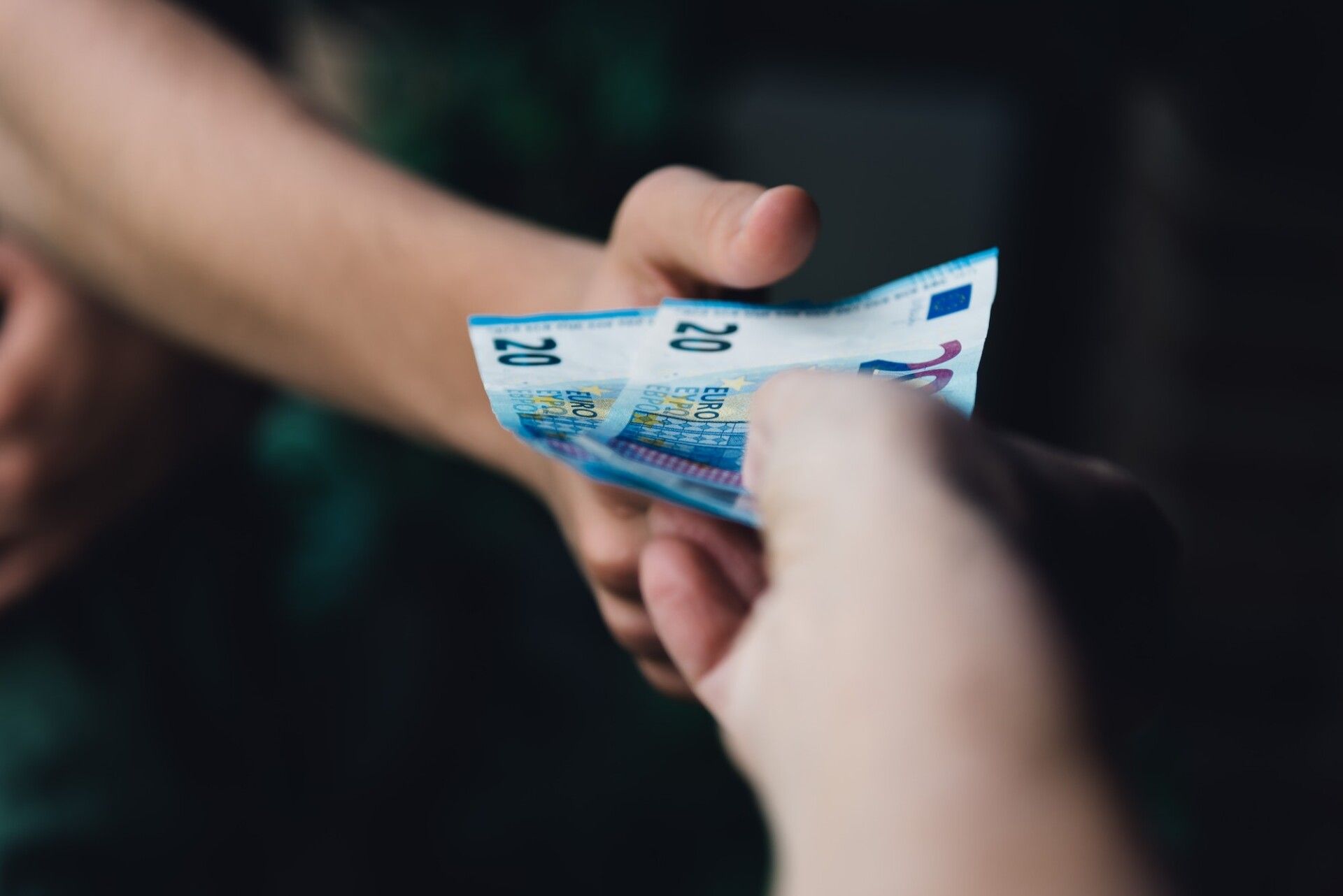 Hand of woman is giving euro money to a young man hand.