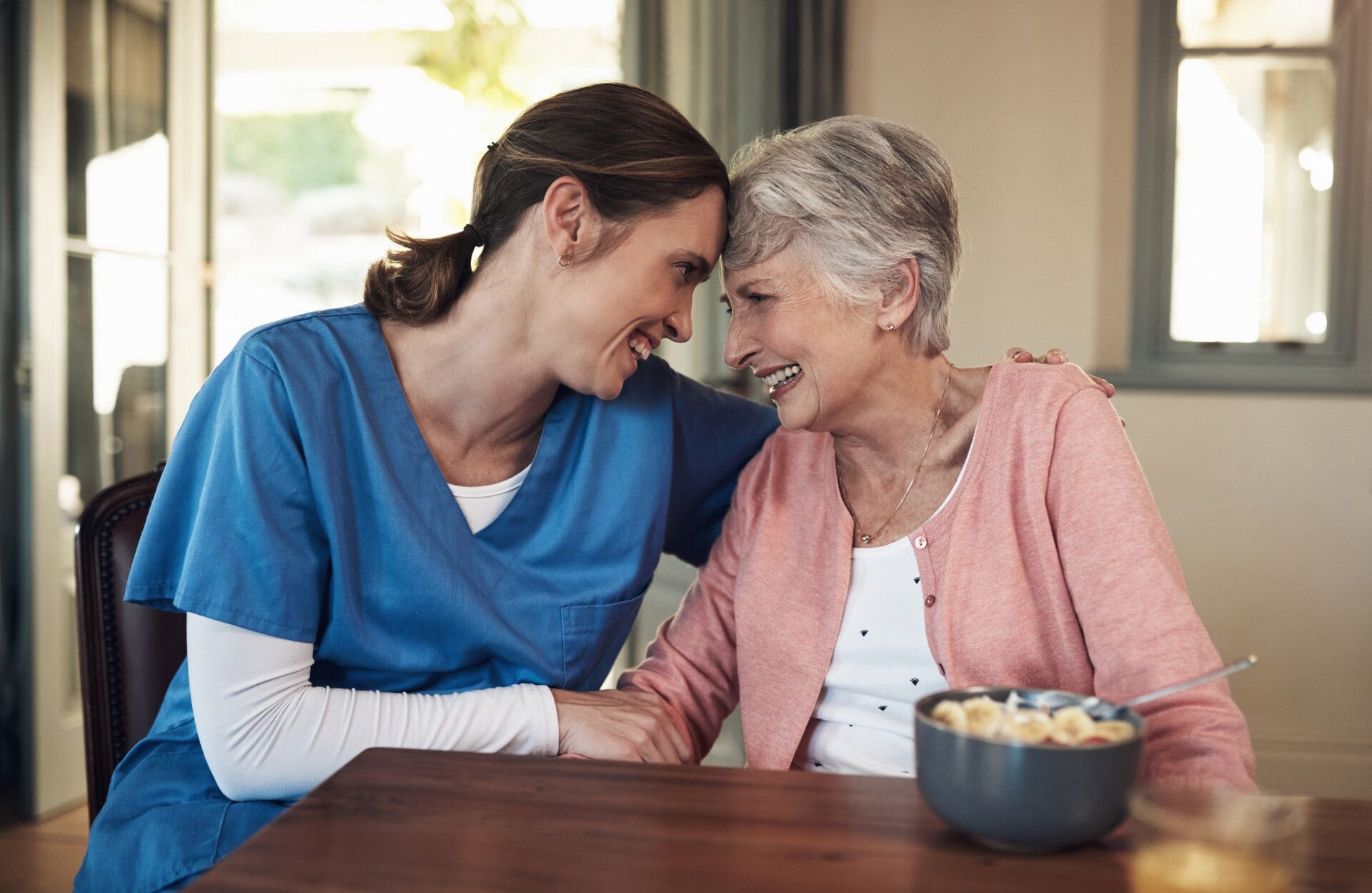 Shot of a young nurse sitting with a senior woman at breakfast time in a nursing home