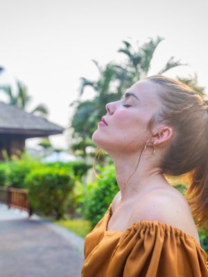 A girl meditates and breathes fresh air while in public park