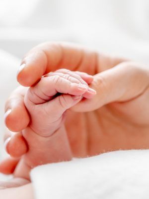 Mother holding newborn baby hand
