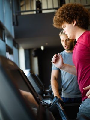 Overweight young man exercising gym with personal trainer